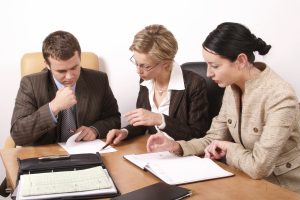 3 people meeting with paperwork