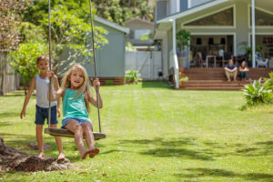 kids playing on wooden swing in a backyard