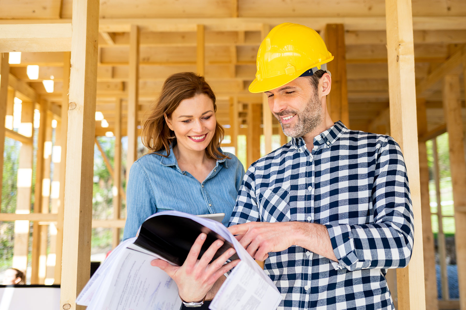 Homeowner meeting with architect or engineer on construction site of her new house looking at blueprints